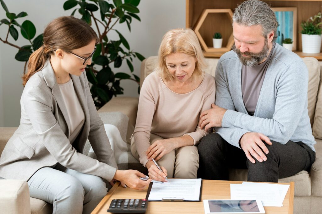 Young agent pointing at place for signature while mature client signing document