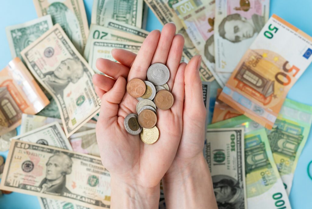 The girl holds coins in her hands against the background of scattered banknotes.